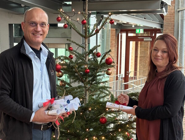 Bild vergr&ouml;&szlig;ern: Man sieht B&uuml;rgermeister W&uuml;nstel mit der Gemeindeschwesterplus Baudy mit den Briefen vor einem Weihnachtsbaum.
