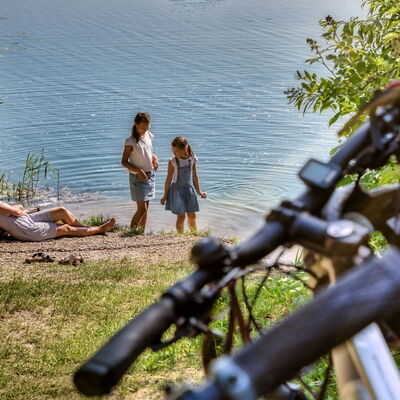 Bild vergrößern: Familie macht Rast am Baggersee Neupotz, Fahrradlenker im Vordergrund