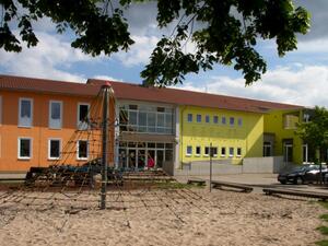 Bild vergrößern: Grundschule An der Römerstraße Rheinzabern, Außenansicht mit Spielplatz im Vordergrund.